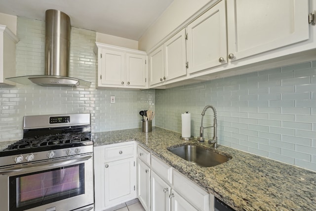 kitchen with stainless steel gas range, a sink, white cabinets, wall chimney range hood, and backsplash