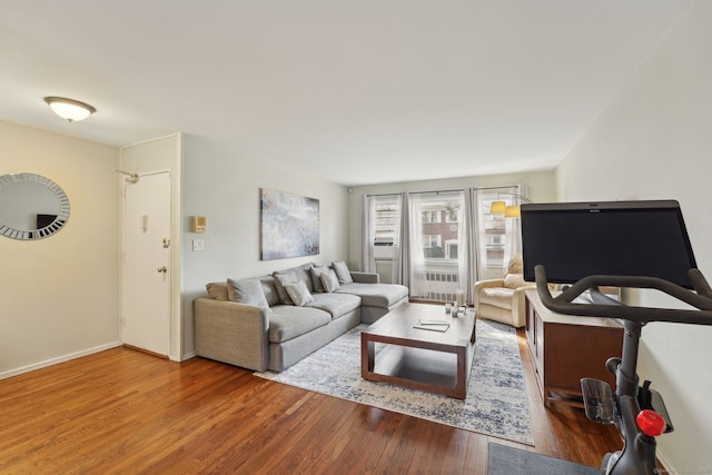 living area with radiator heating unit, wood finished floors, and baseboards