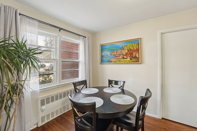 dining area with radiator heating unit, wood finished floors, and baseboards