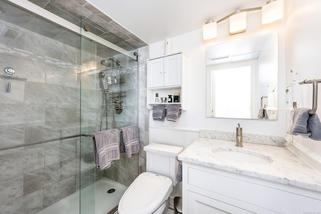 bathroom featuring vanity, toilet, and a shower with shower door