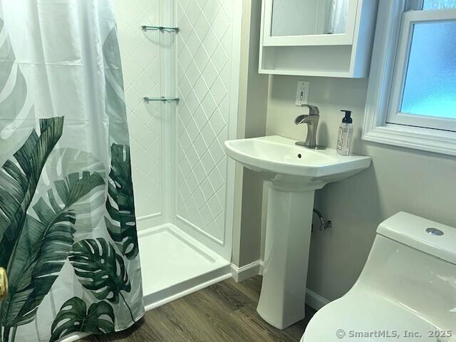 bathroom with hardwood / wood-style floors, toilet, and walk in shower