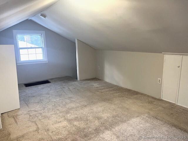 bonus room with light carpet and vaulted ceiling