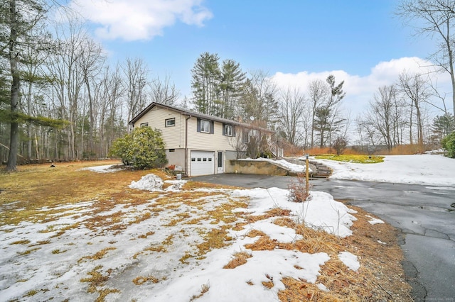 view of snow covered exterior featuring driveway and an attached garage