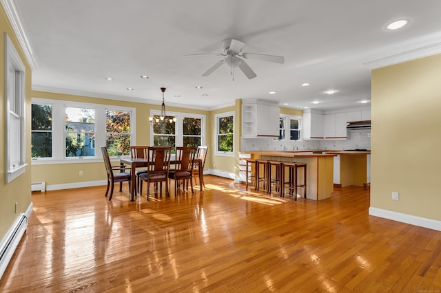 dining room with baseboard heating, ornamental molding, ceiling fan with notable chandelier, and light hardwood / wood-style flooring