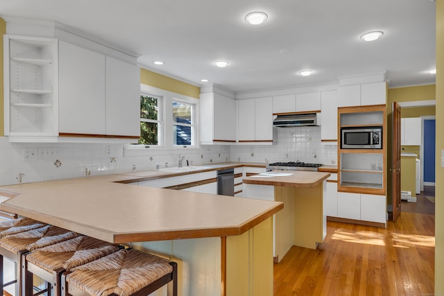 kitchen featuring white cabinetry, stainless steel microwave, a kitchen breakfast bar, and kitchen peninsula