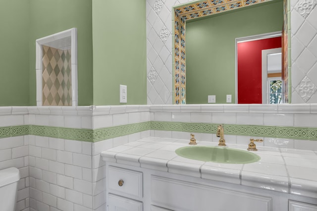 bathroom with vanity, toilet, and tile walls