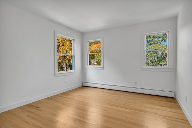 empty room featuring a baseboard radiator and light wood-type flooring