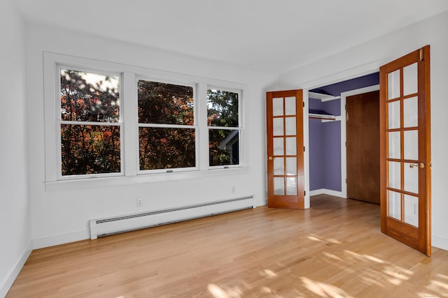 empty room featuring light hardwood / wood-style floors, baseboard heating, and french doors