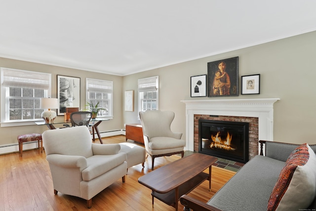 living room with light hardwood / wood-style flooring, a baseboard heating unit, ornamental molding, and a fireplace