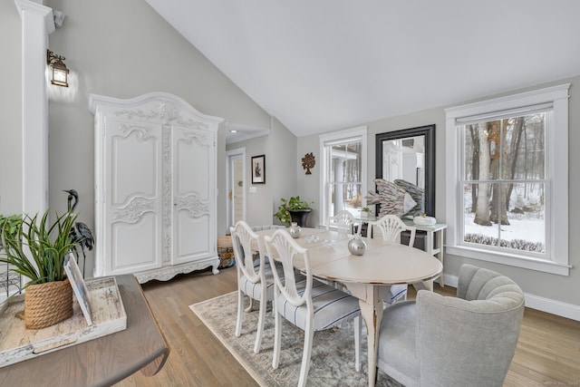 dining space with a wealth of natural light, lofted ceiling, baseboards, and wood finished floors