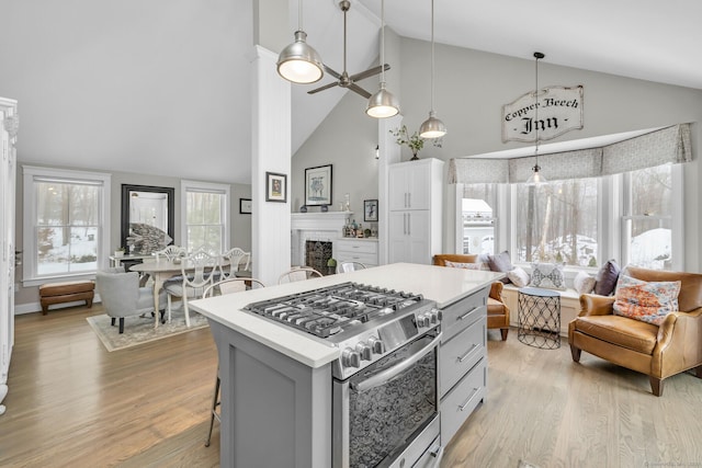 kitchen with pendant lighting, light countertops, open floor plan, gas range, and a kitchen breakfast bar