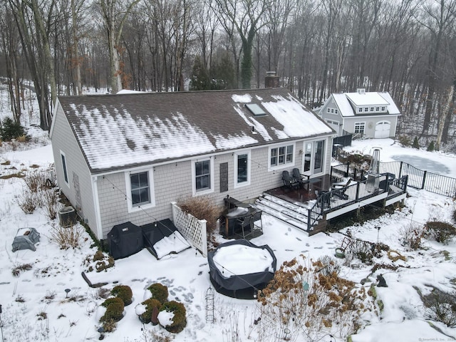 snow covered property with a shingled roof, a chimney, cooling unit, and a wooden deck