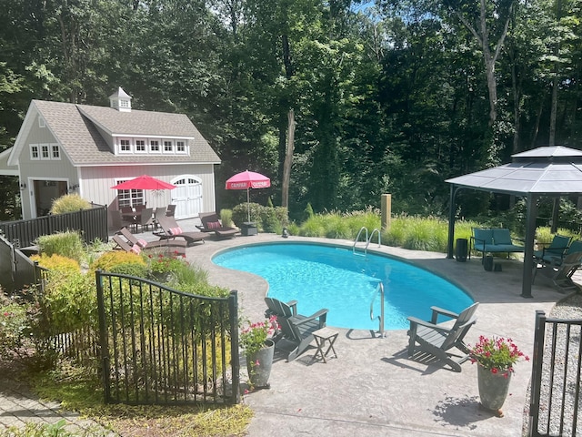 outdoor pool featuring an outbuilding, a patio area, fence, and a storage structure