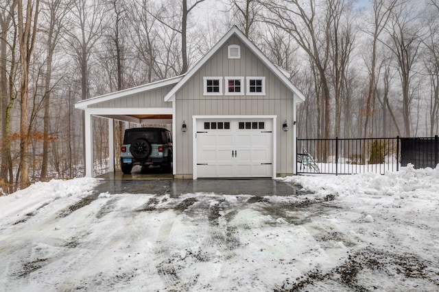 snow covered garage with a garage, fence, and a carport