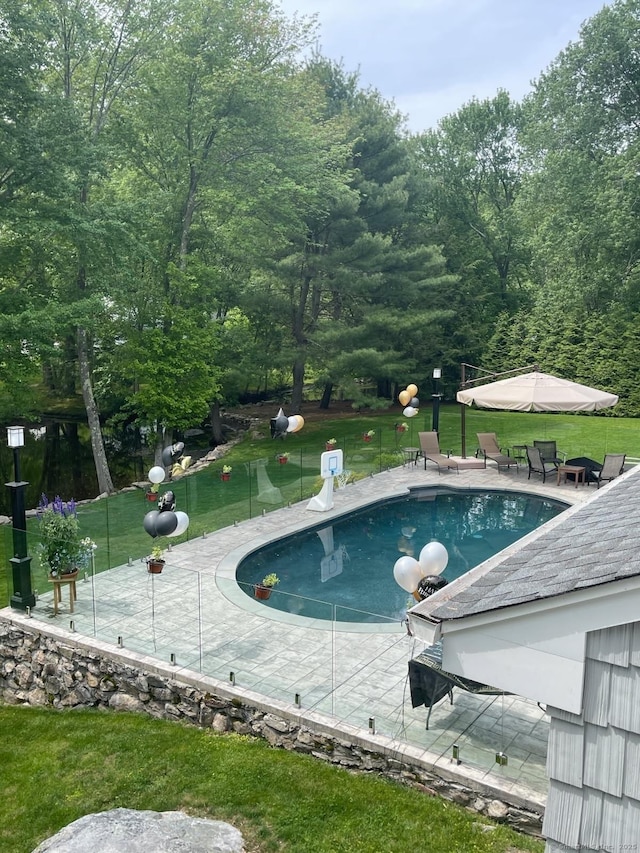 outdoor pool with a patio and a lawn