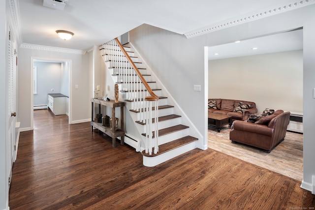 stairs with a baseboard heating unit, crown molding, wood finished floors, and baseboards