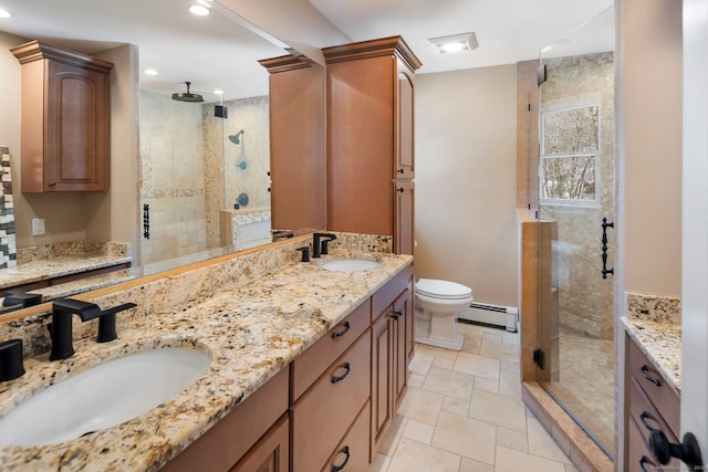 bathroom featuring double vanity, a shower stall, a baseboard heating unit, and a sink