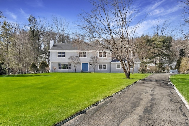 colonial-style house with a chimney and a front lawn