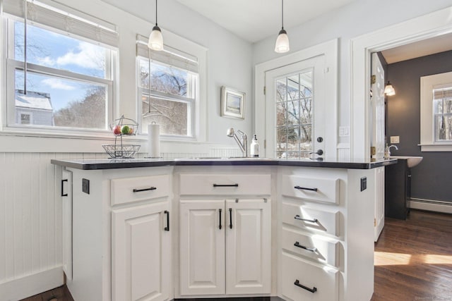 kitchen featuring white cabinetry, dark hardwood / wood-style flooring, kitchen peninsula, and pendant lighting