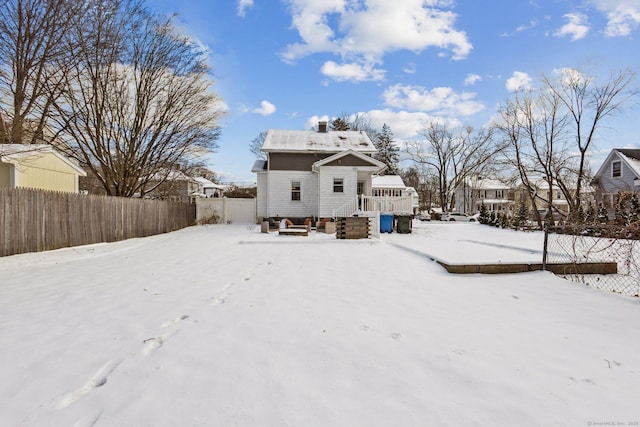 snow covered back of property with a deck