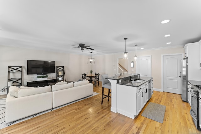 kitchen with an island with sink, appliances with stainless steel finishes, white cabinets, and hanging light fixtures