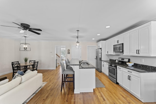 kitchen featuring sink, white cabinetry, stainless steel appliances, and pendant lighting