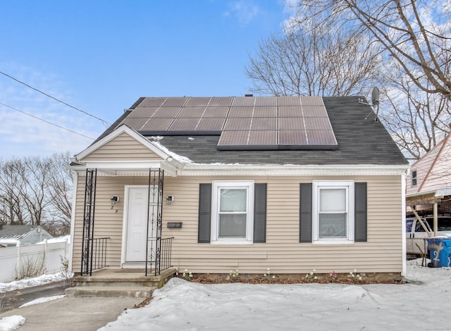 view of front of home featuring fence and roof mounted solar panels