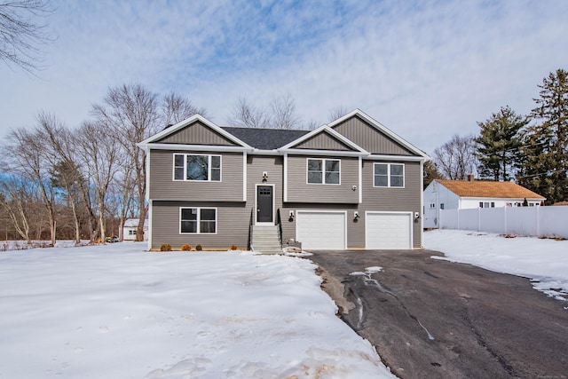 split foyer home with an attached garage, fence, aphalt driveway, and board and batten siding