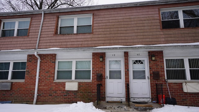 townhome / multi-family property featuring entry steps, brick siding, and mansard roof