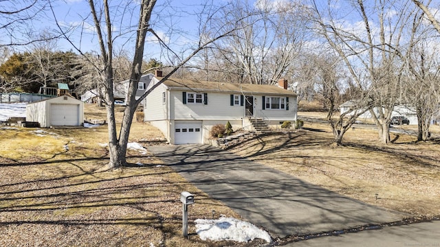 bi-level home featuring entry steps, an outbuilding, an attached garage, driveway, and a chimney