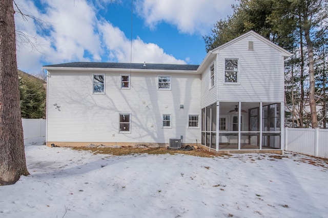 snow covered rear of property featuring cooling unit, a sunroom, fence, and ceiling fan