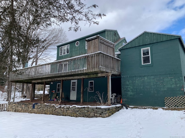 snow covered back of property featuring a deck