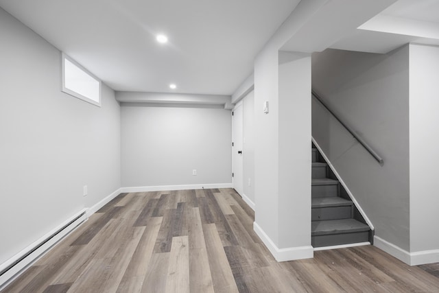 basement with wood-type flooring and baseboard heating