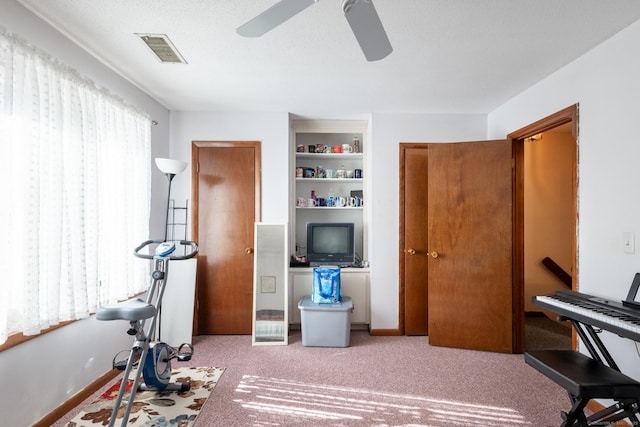 workout room featuring carpet floors, ceiling fan, visible vents, and baseboards