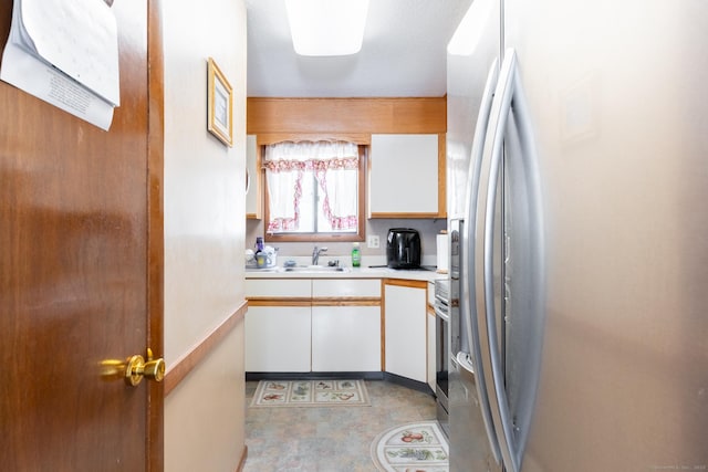 kitchen featuring a sink, stainless steel appliances, light countertops, and white cabinets