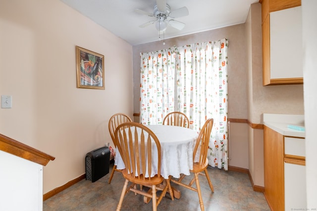 dining space with a ceiling fan and baseboards