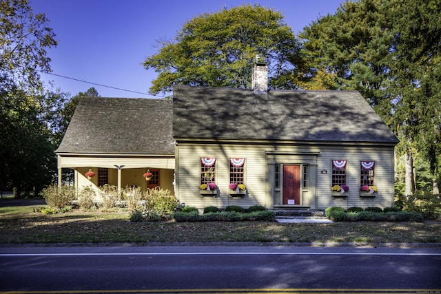 cape cod home featuring a chimney and a shingled roof