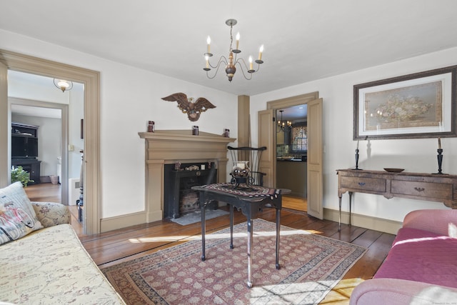 living room with a fireplace with flush hearth, baseboards, an inviting chandelier, and wood-type flooring