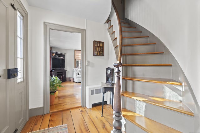 staircase with a wealth of natural light, radiator heating unit, and hardwood / wood-style flooring