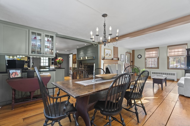 dining space with radiator, a fireplace, light wood-type flooring, and a wealth of natural light