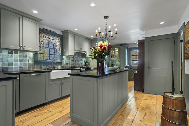 kitchen featuring dark countertops, gray cabinetry, a kitchen island, light wood-style flooring, and a sink