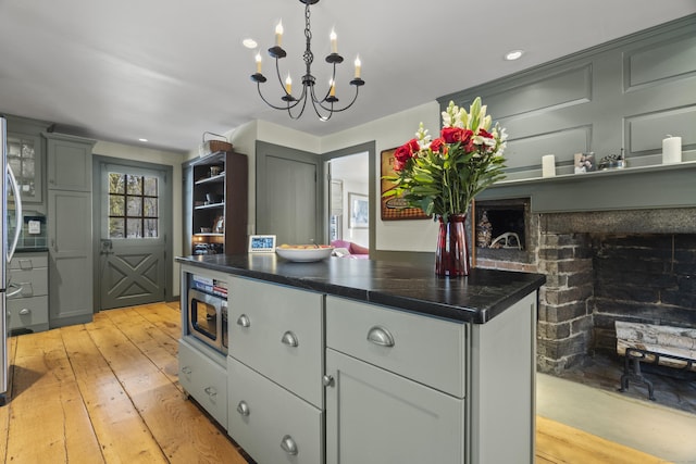 kitchen with stainless steel microwave, dark countertops, light wood-style floors, and gray cabinets