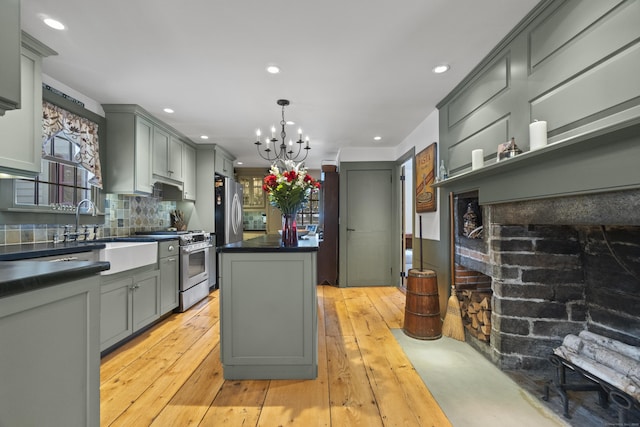 kitchen featuring gray cabinets, dark countertops, a center island, stainless steel appliances, and an inviting chandelier