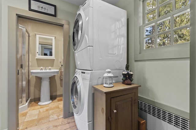 laundry area featuring laundry area, stacked washing maching and dryer, radiator heating unit, and baseboards