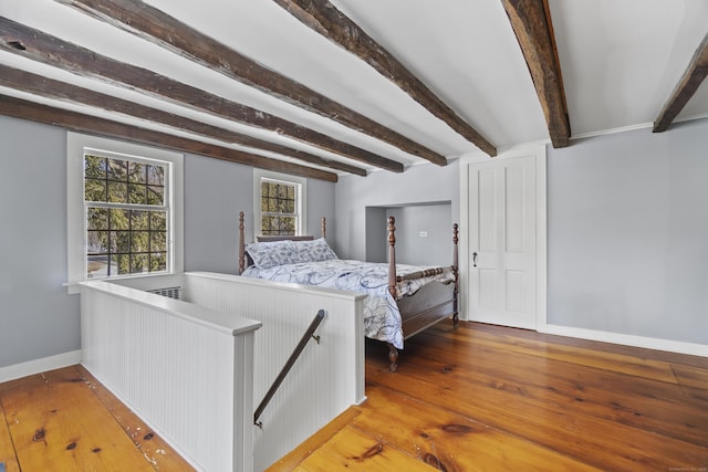 bedroom featuring beamed ceiling, baseboards, and wood-type flooring