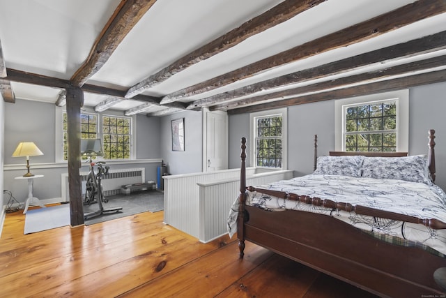 bedroom featuring wood-type flooring, beam ceiling, and radiator heating unit