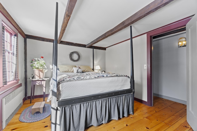 bedroom featuring beamed ceiling, radiator, baseboards, and hardwood / wood-style flooring