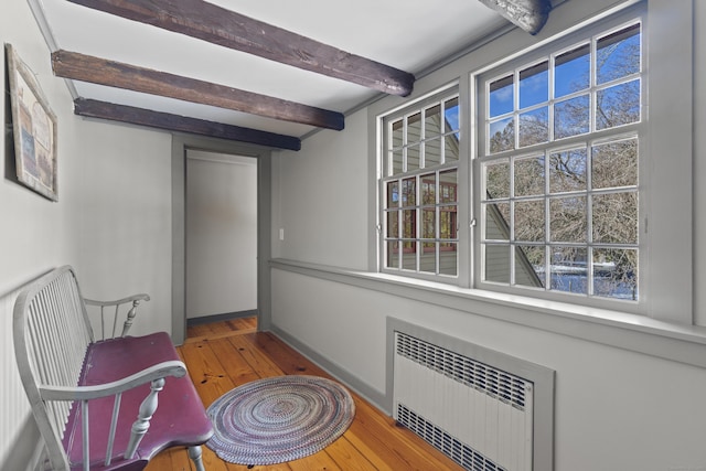 sitting room with beamed ceiling, wood-type flooring, baseboards, and radiator heating unit