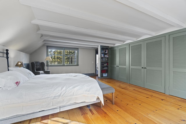 bedroom with vaulted ceiling with beams and hardwood / wood-style floors