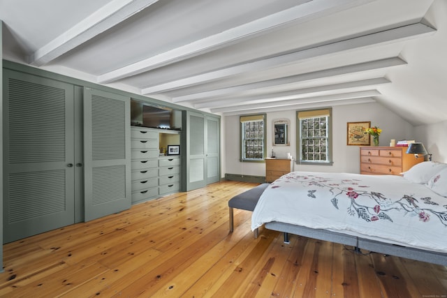 bedroom with two closets, lofted ceiling with beams, and hardwood / wood-style flooring